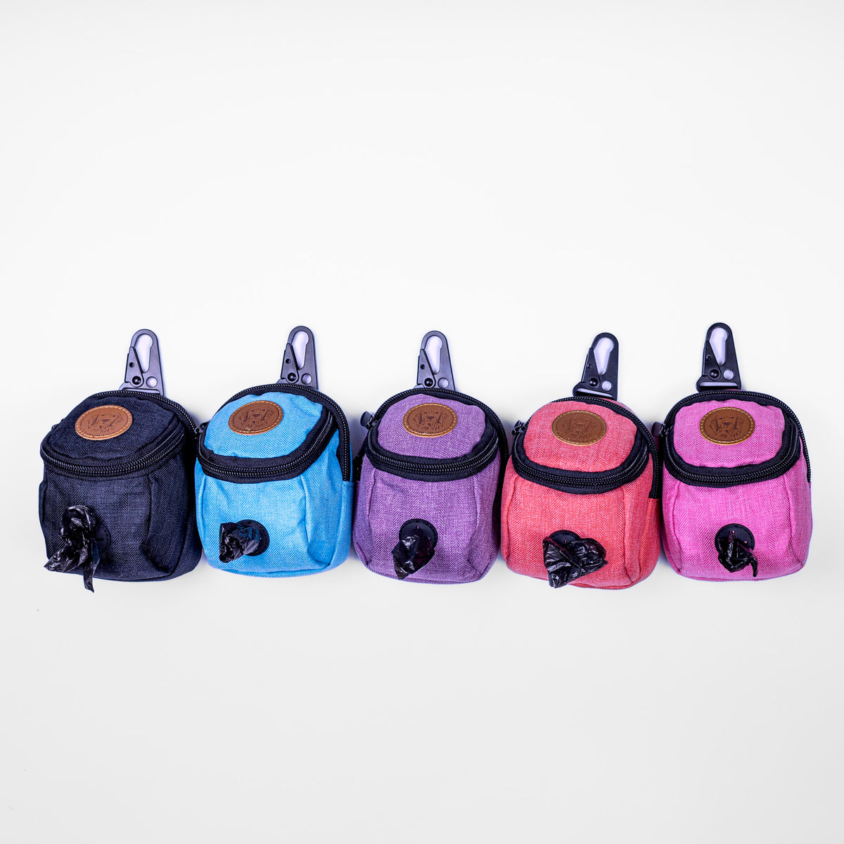 Five colorful dog waste bag holders in a row on a white background.