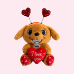 Plush dog toy with heart-shaped antennas and 'I love you' heart on a light pink background