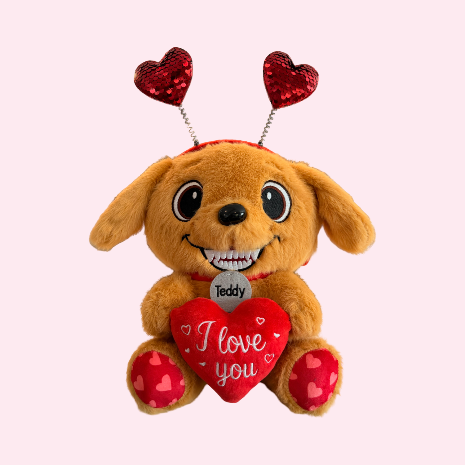 Plush dog toy with heart-shaped antennas and 'I love you' heart on a light pink background