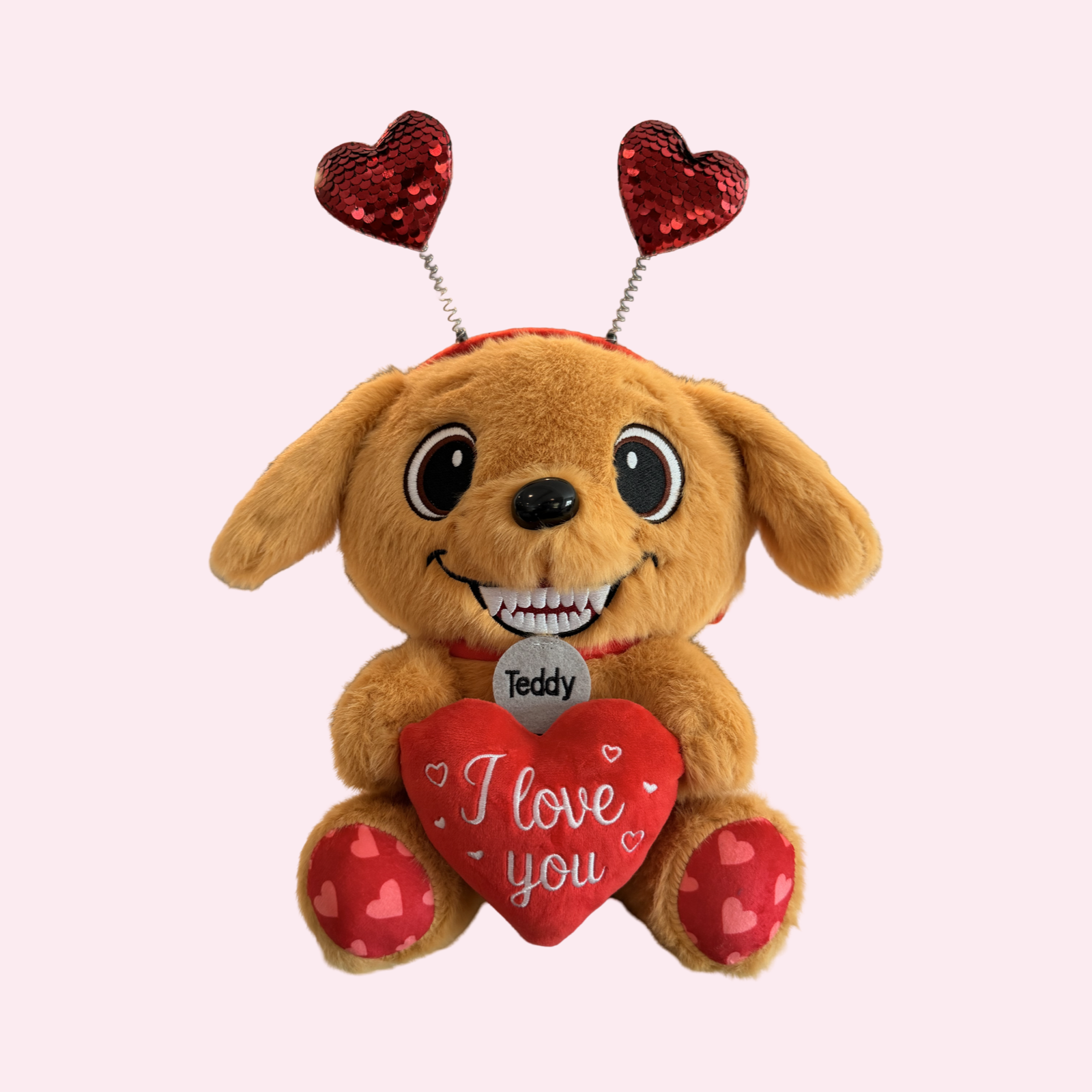 Plush dog toy with heart-shaped antennas and 'I love you' heart on a light pink background